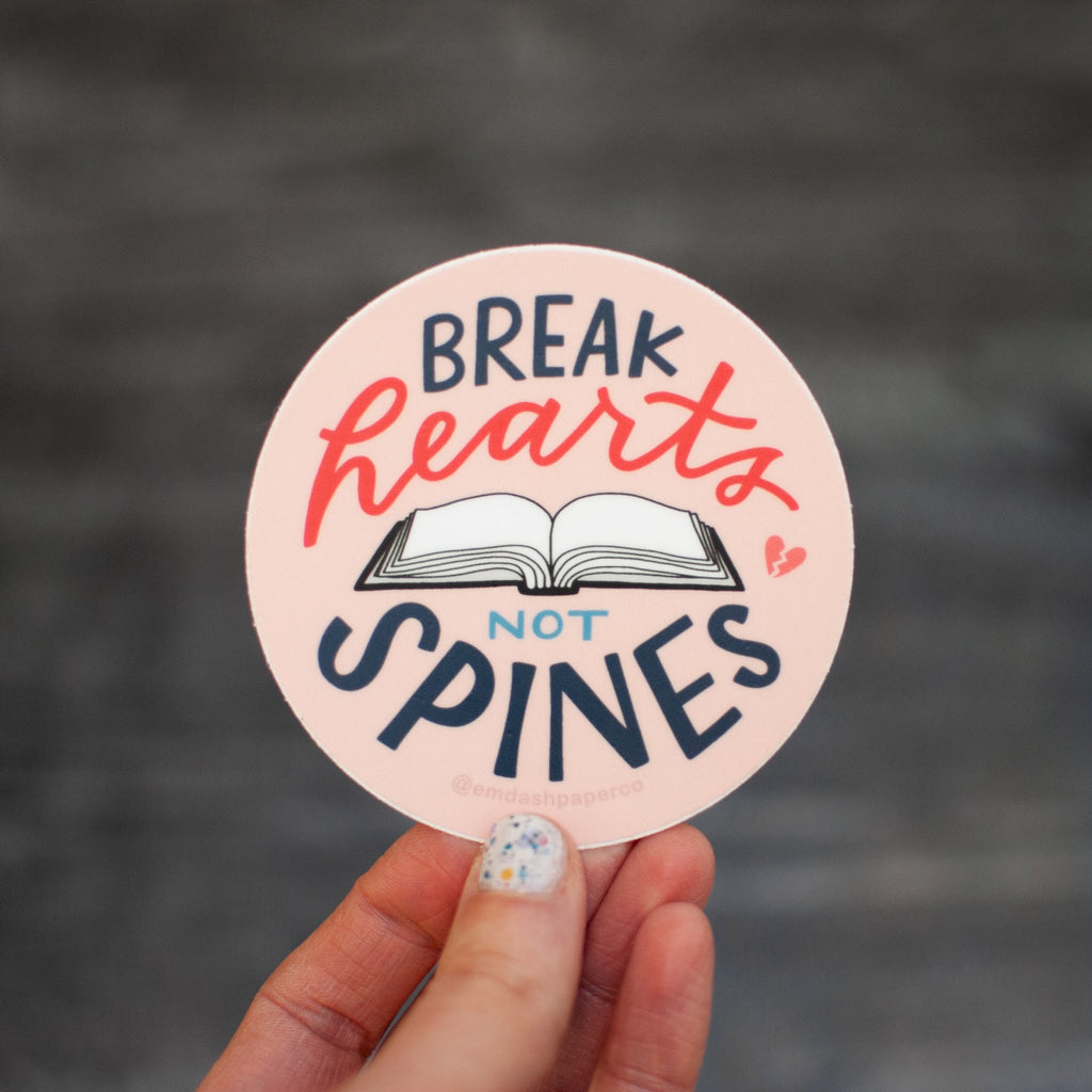 Break hearts, not spines! This 3-inch round weather-resistant vinyl sticker was hand drawn and lettered by Em Dash Paper Co. for book lovers everywhere.