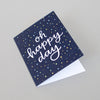 Oh happy day! Modern calligraphy on navy blue background with yellow and green confetti.
