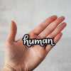 Human sticker, hand lettered in stylized script by Emily Poe-Crawford of Em Dash Paper Co. Measures about 3
